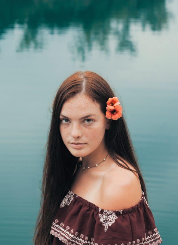 Portrait d'une femme au bord d'un lac avec une fleur dans les cheveux